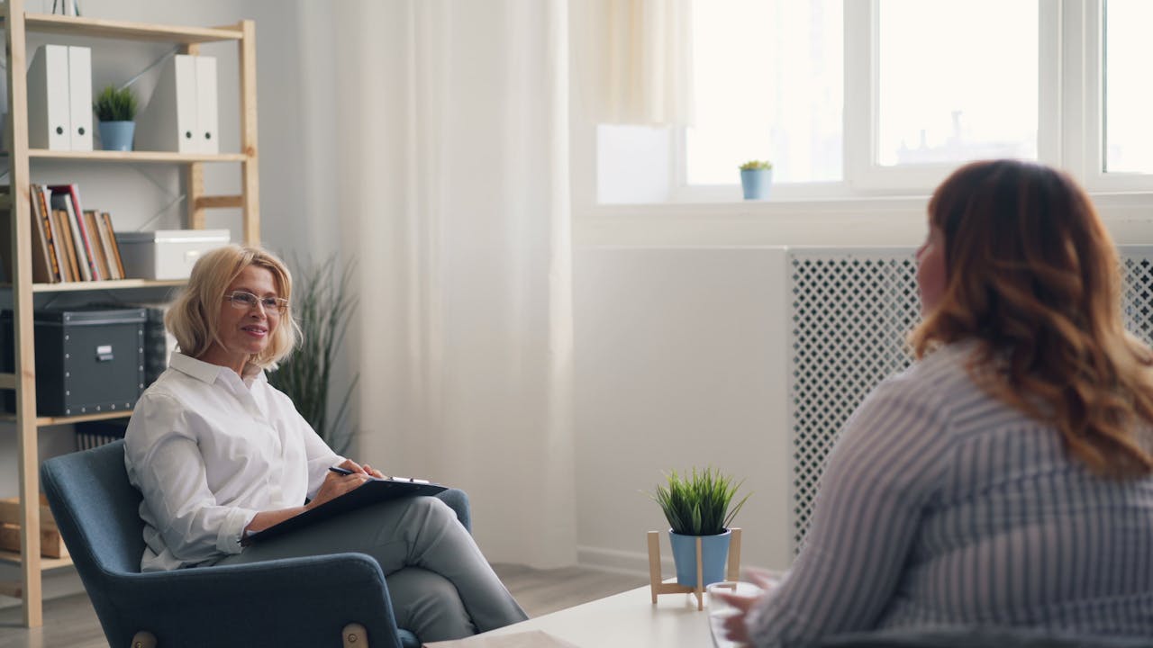 A therapist and a client engaging in a counseling session in a bright, modern office.